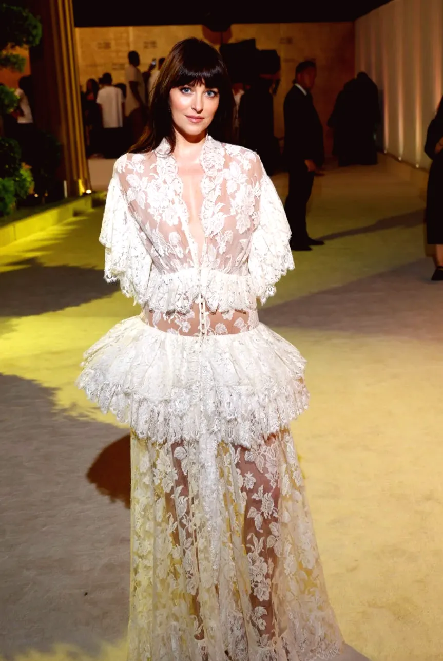 Dakota Johnson in Semi-Sheer White Gown With Tiered Lace Skirt